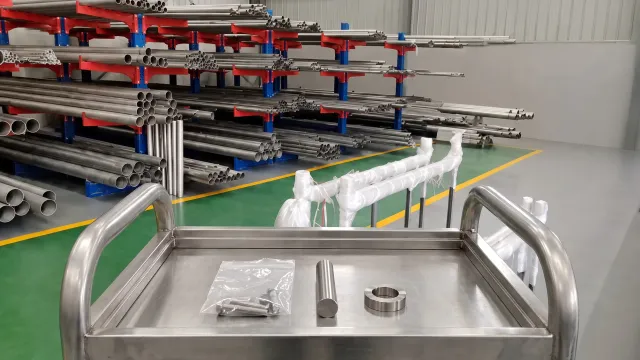 Small group of titanium items on a cart in front of organized tube and bar stock