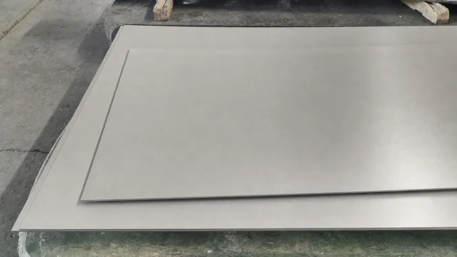Several flat titanium plates stacked on a workshop table