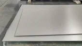 Several flat titanium plates stacked on a workshop table