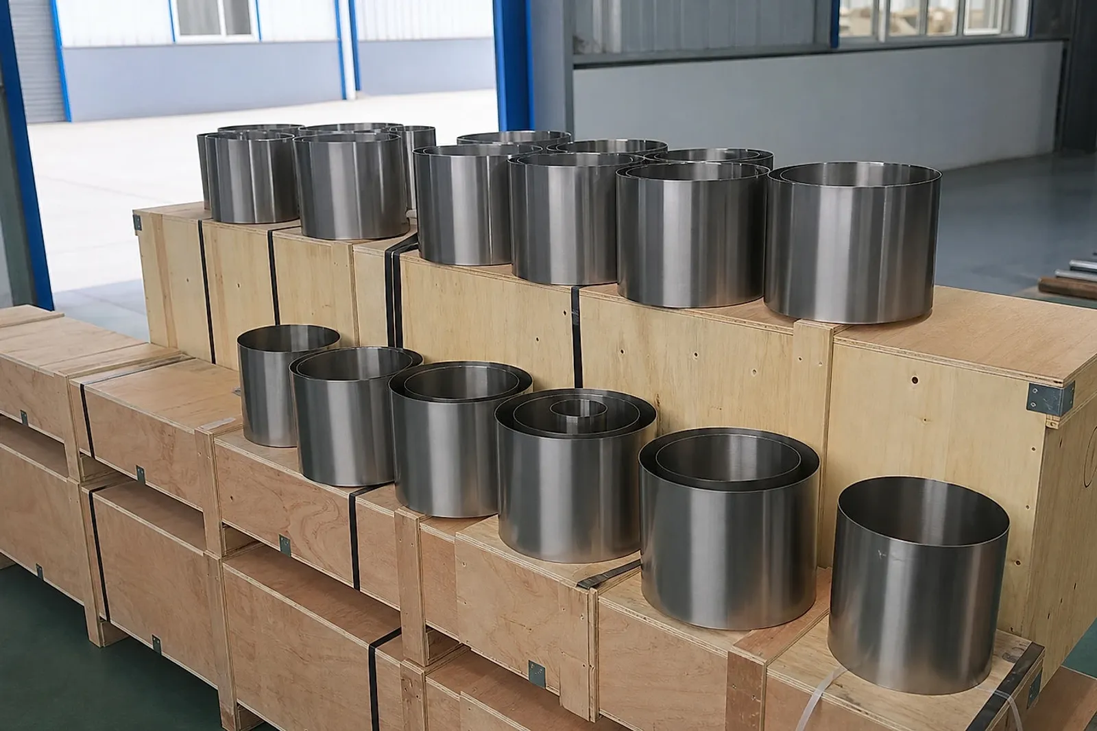 Titanium cylindrical parts staged on export crates, illustrating why AM buyers need batch identity and release data before acceptance.