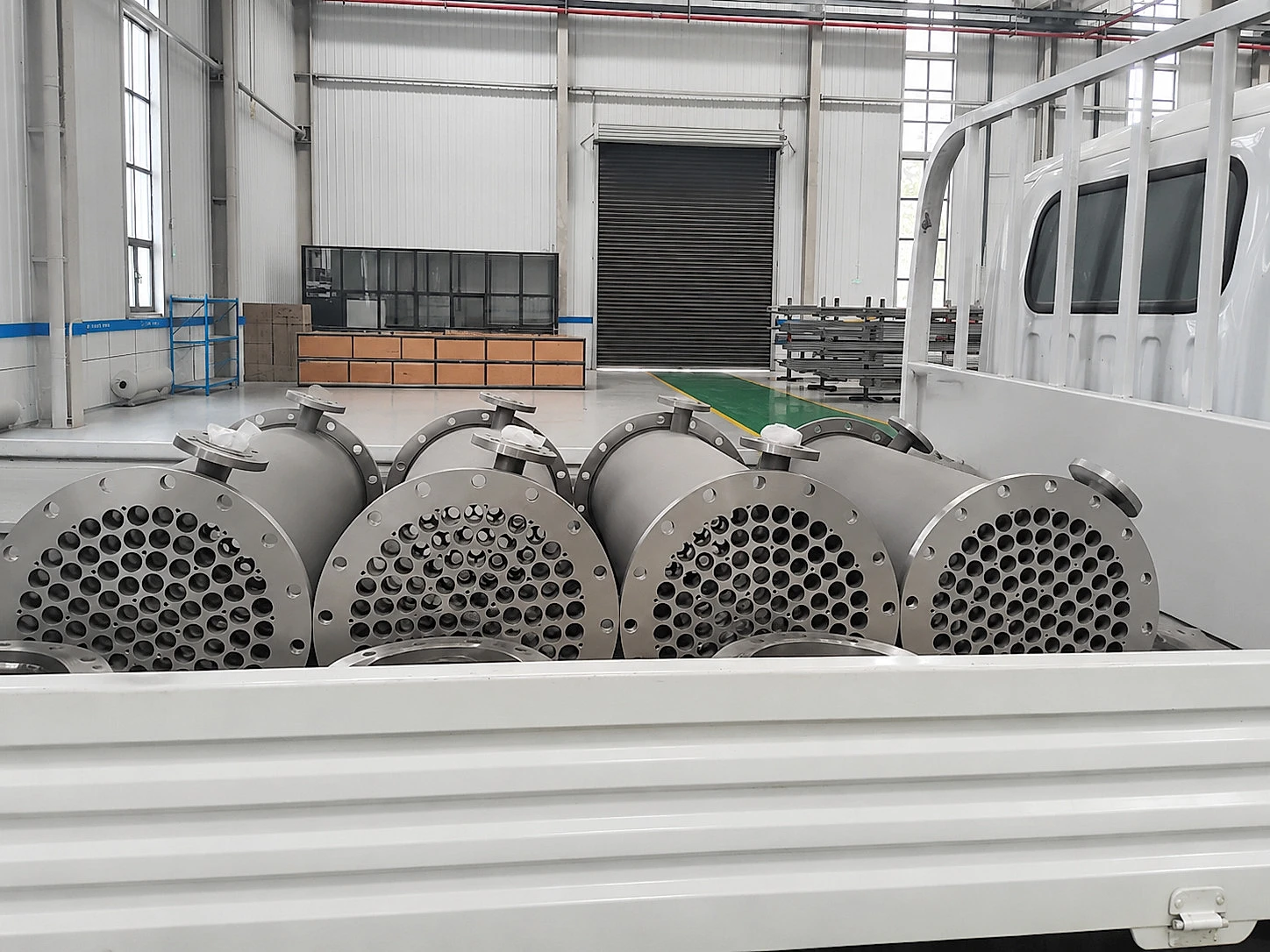 Titanium tube-sheet assemblies prepared for transport, showing that buffered intermediaries still require conversion, inspection, packaging, and release capacity.