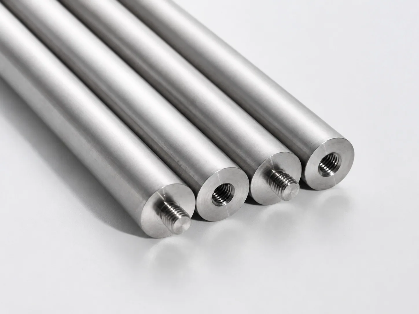Four machined metal rods with alternating external and internal threaded ends