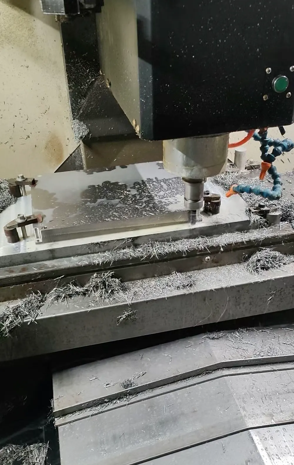 CNC milling machine cutting titanium plate with coolant nozzle and chip buildup