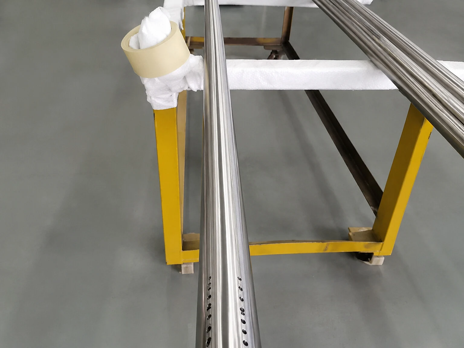 Titanium-like precision rails on a protected rack, showing the material identity layer that should stay linked to AM acceptance data.