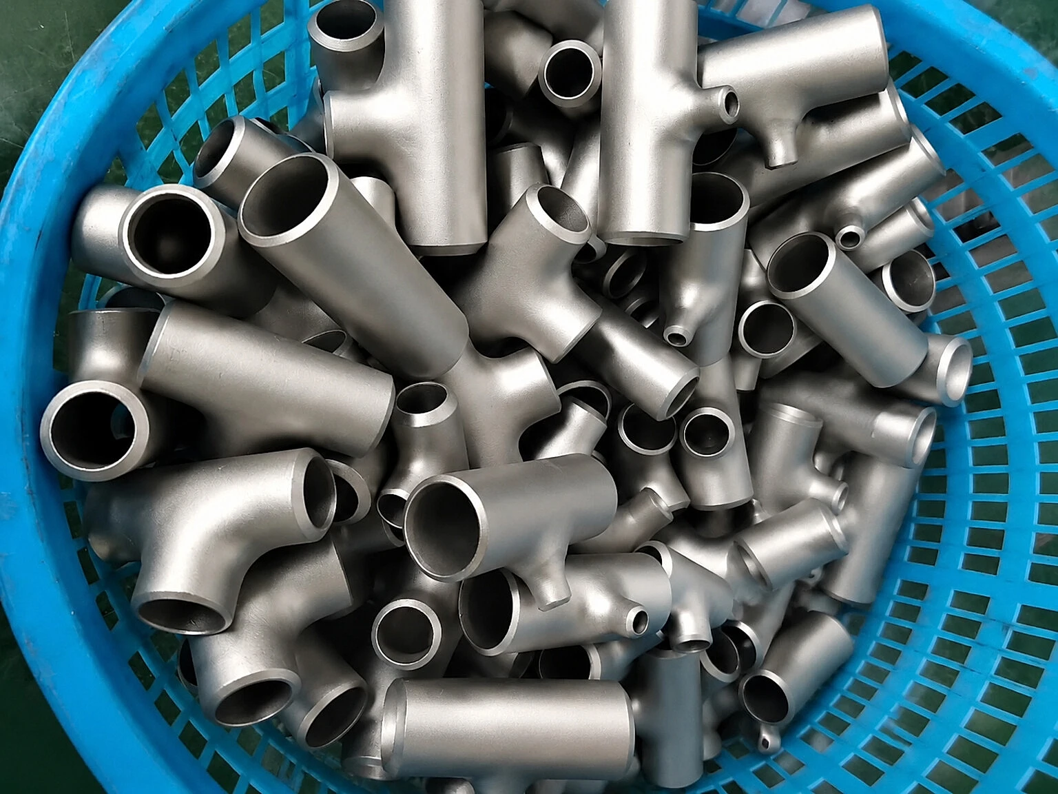 Complex titanium-like small-batch components in a workshop basket, used here to illustrate that parts still need lot, route and release records after capacity changes.