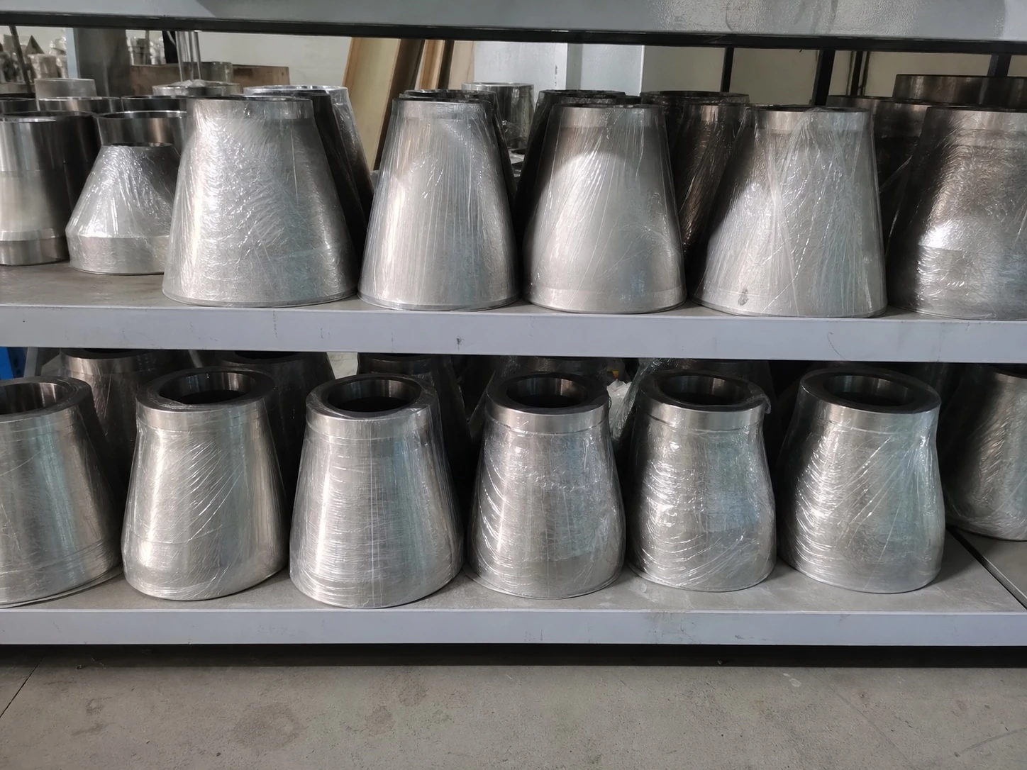 Wrapped titanium reducer fittings on storage shelves show how finished geometry and certificate scope sit downstream of mineral feedstock.