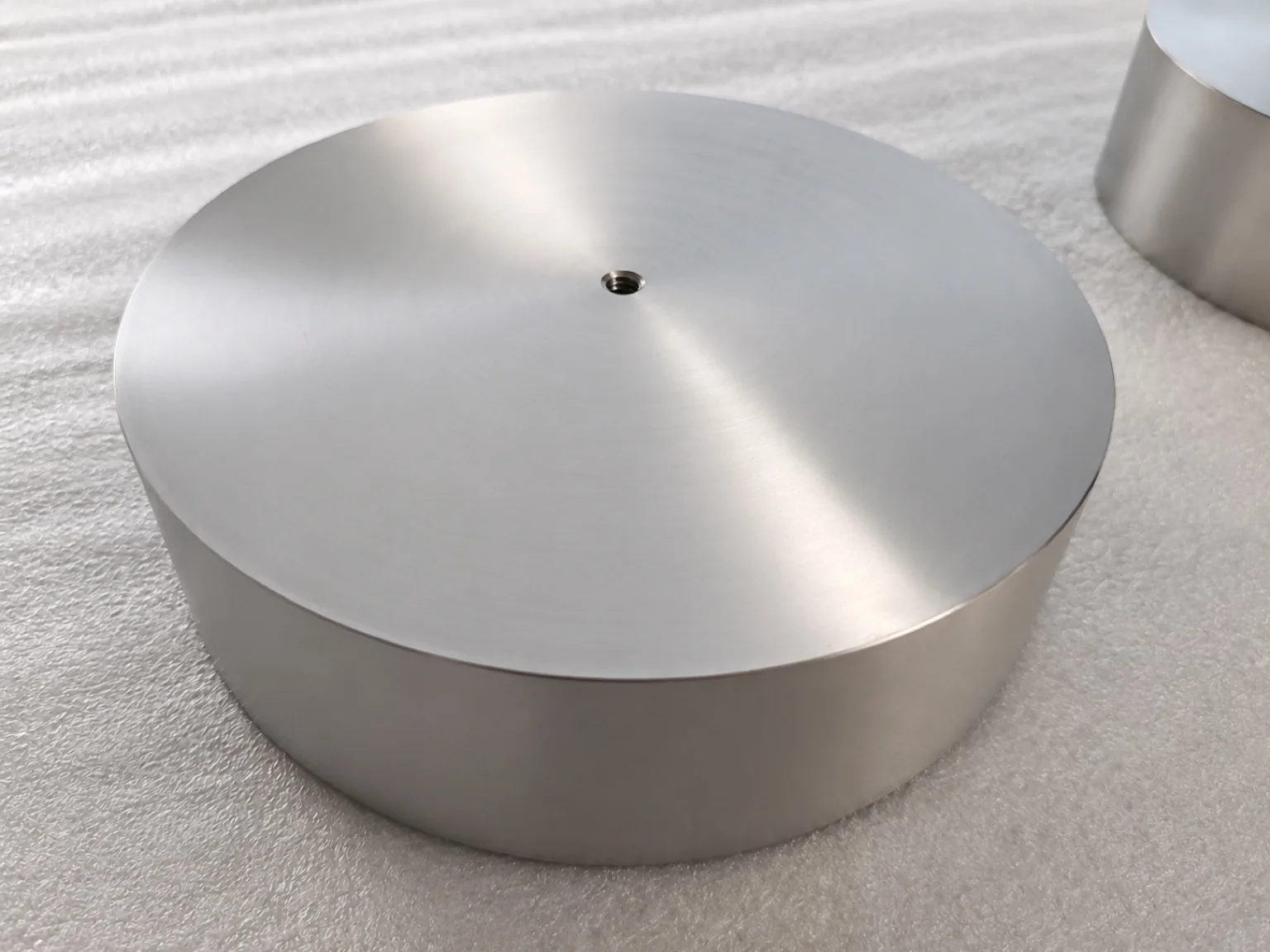 User-owned finished titanium disc illustrates a controlled surface; it is not the material, geometry or specimen used in the reported laser study.