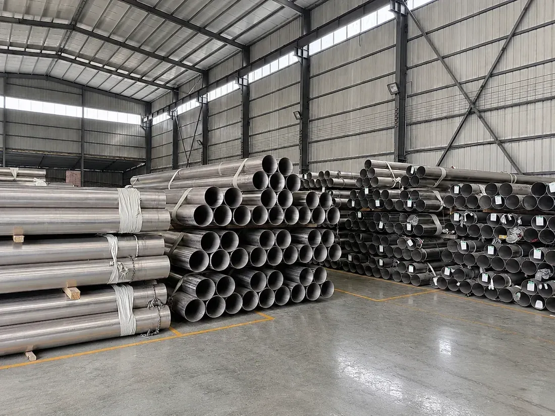 Titanium tubes stockpiled in a downstream mill warehouse — the actual product form titanium buyers purchase, several conversion steps removed from upstream mineral sands.