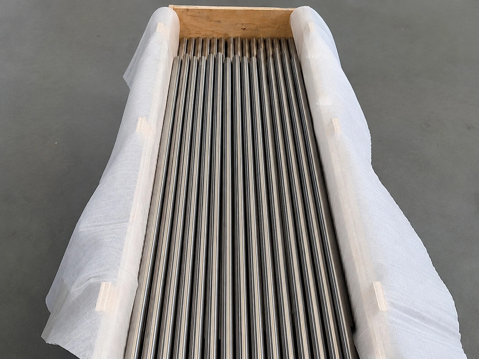 Packed titanium round stock in a crate, showing why material identity and lot records must travel with distributed manufacturing work.