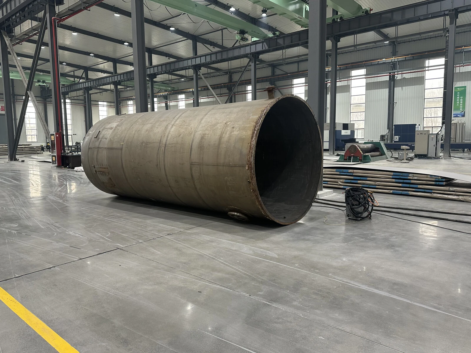 Large cylindrical titanium fabrication shell in a workshop, showing the equipment boundary where tube, plate, machining, welding, and inspection evidence have to meet.